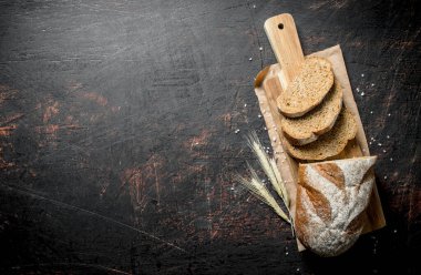 Sivri uçlu dilimlenmiş taze ekmek. Koyu rustik arka plan üzerinde