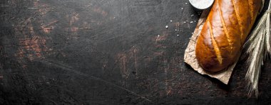 Sivri uçlu ve tuzlu gevrek ekmek. Koyu rustik arka plan üzerinde