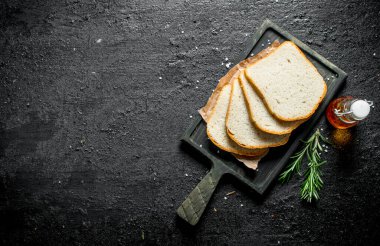 Biberiye ve yağ ile kesme Tahtası üzerinde ekmek parçaları. Siyah rustik arka plan üzerinde