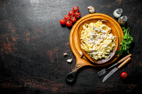 stock image Pasta fettuccine with Carbonara sauce on a plate and tomatoes with spices. On rustic background