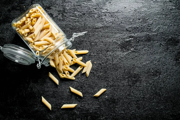 stock image Dry pasta in a glass jar. On black rustic background