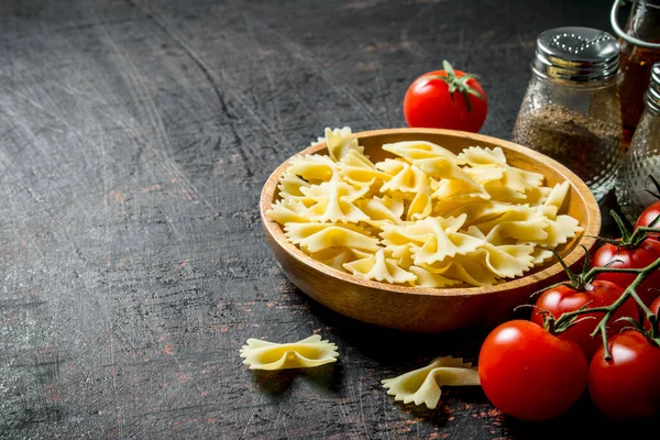 Pasta Farfalle Crua Tigela Com Tomates Especiarias Fundo Rústico Preto — Fotografia de Stock