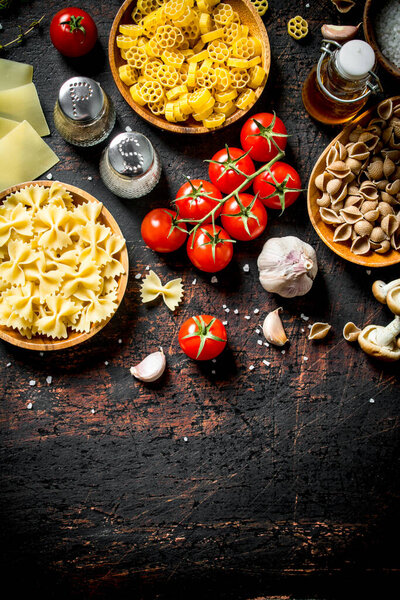 Different types of raw paste in bowls with garlic, tomatoes and spices. On rustic background