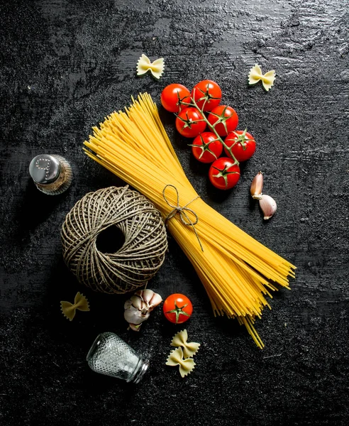 トマト スパイス 古い糸の生スパゲッティ 黒い素朴な背景に — ストック写真