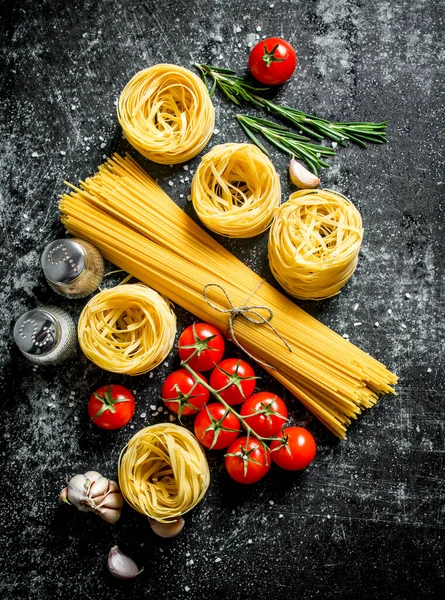 生のタリアテルとスパゲッティのスパイス トマト ローズマリー 黒い素朴な背景に — ストック写真