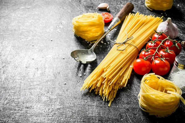 生のスパゲッティとタリアテルのチェリートマト ニンニク 黒い素朴な背景に — ストック写真
