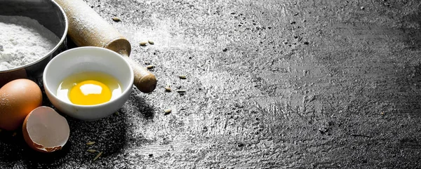 stock image Flour with egg in bowls. On black rustic background