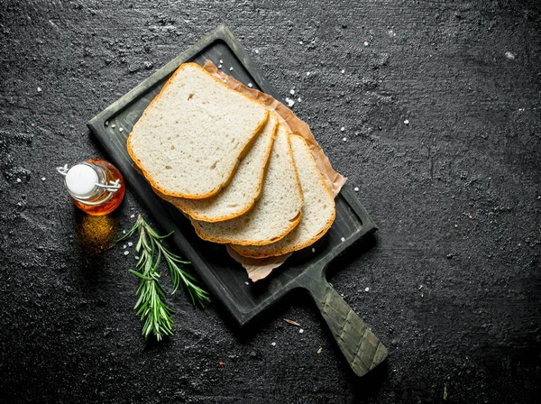 stock image Pieces of fresh bread with rosemary. On black rustic background