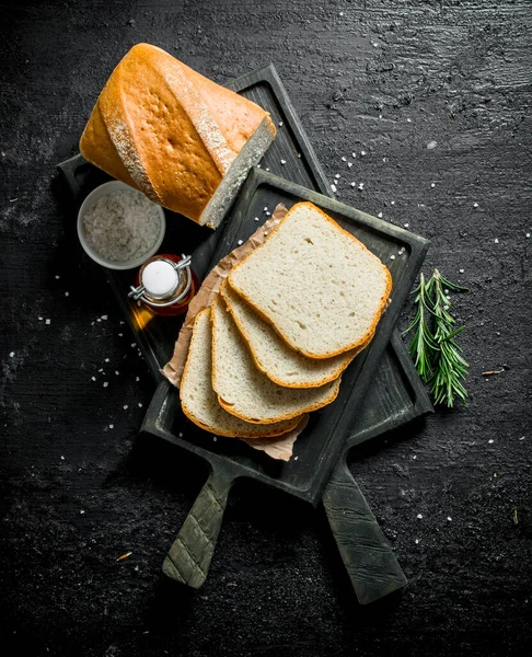 stock image Bread with rosemary and oil on the cutting Board. On black rustic background