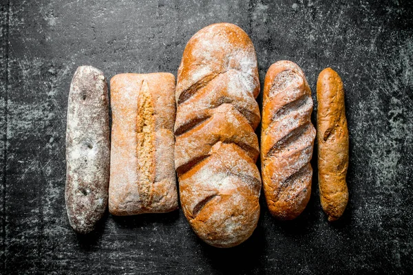 Stock image Assortment of different types of fresh bread. On dark rustic background