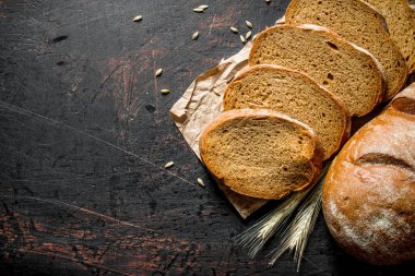 Dilimlenmiş taze ekmek. Koyu rustik arka plan üzerinde