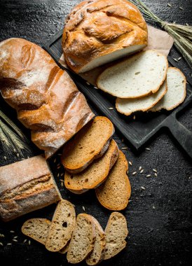 Farklı ekmek türlerinin parçaları. Siyah rustik arka plan üzerinde