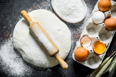 Yumurta, un ve oklava ile Hamur. Koyu rustik arka plan üzerinde