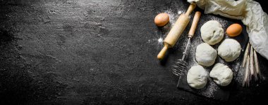 Yumurta ve oklava ile hamur yuvarlak parçalar. Siyah rustik arka plan üzerinde