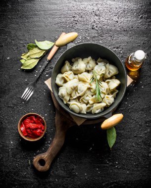 Bay yaprağı olan bir tencerede sığır köftesi. Siyah rustik arka plan üzerinde