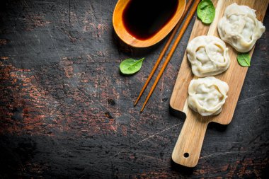 Soya soslu bir kesme tahtası üzerinde Köfte manta. Koyu rustik arka plan üzerinde