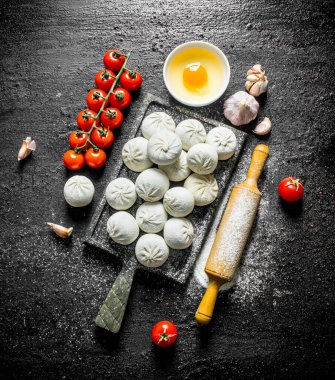 Sarımsak ve domates ile çiğ manta köfte. Siyah rustik arka plan üzerinde