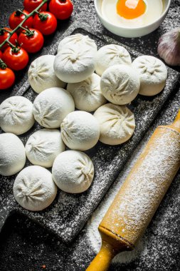 Bir dalüzerinde domates ile çiğ manta köfte. Siyah rustik arka plan üzerinde