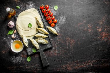 Çiğ gedza köfte yapmak için hamur dışarı haddelenmiş. Koyu rustik arka plan üzerinde