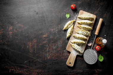 Gedza köfte, kesme tahtasında etli. Koyu rustik arka plan üzerinde