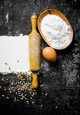 Yumurtalı buğday unu, oklavalı iğne ve tahıl. Koyu kırsal arkaplanda