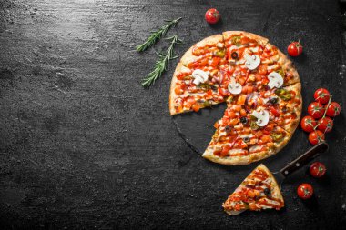 Kiraz domates ve biberiye ile dilimlenmiş Meksika pizzası. Siyah rustik arka plan üzerinde