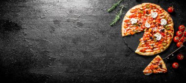 Kiraz domates ve biberiye ile dilimlenmiş Meksika pizzası. Siyah rustik arka plan üzerinde