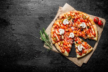 Gazetede Meksika pizzasını kes. Siyah rustik arka plan üzerinde