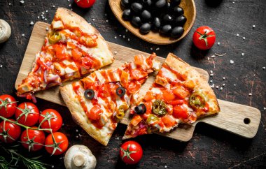 Zeytin, domates ve mantar ile kokulu pizza dilimleri. Koyu rustik arka plan üzerinde