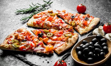 Domates, biberiye ve zeytin ile gevrek pizza. Koyu rustik arka plan üzerinde