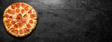 Salamlı dilimlenmiş biberli pizza. Siyah rustik arka plan üzerinde