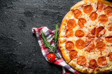Peçetede gevrek biberli pizza. Siyah rustik arka plan üzerinde