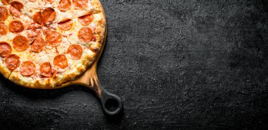 Taze pişmiş pepperoni pizza. Siyah rustik arka plan üzerinde