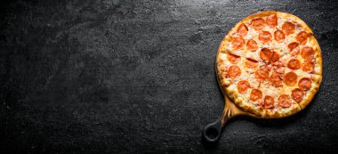 Taze pişmiş pepperoni pizza. Siyah rustik arka plan üzerinde
