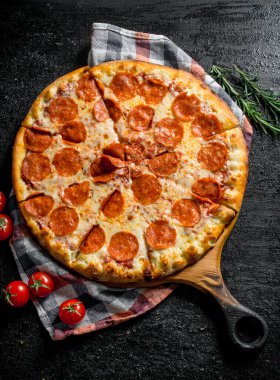 Biberiye ve domates ile dilimlenmiş pepperoni pizza. Rustik arka planda