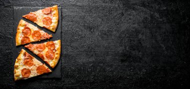 Sosis ve peynir ile pepperoni pizza dilimleri. Siyah rustik arka plan üzerinde