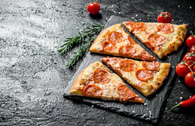 Taş tahtada kokulu biberli pizza dilimleri. Siyah rustik arka plan üzerinde