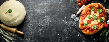 Pizza hamuru ve hazır ev yapımı pizza. Koyu rustik arka plan üzerinde