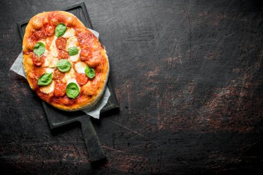 Sosis, domates ve peynirli ev yapımı pizza. Koyu rustik arka plan üzerinde