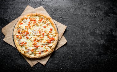 Kağıt üzerinde tavuk, domates ve peynir soslu pizza. Siyah rustik arka plan üzerinde