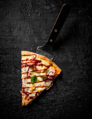 Bir parça kokulu barbekü pizzası. Siyah rustik arka plan üzerinde
