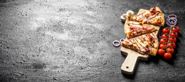 Bir dalda domates li dilimlenmiş barbekü pizzası. Siyah rustik arka plan üzerinde