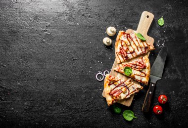 Kiraz domates ve soğan halkaları ile Barbekü pizza dilimleri. Siyah rustik arka plan üzerinde