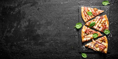 Pastırma, tavuk ve peynir ile Barbekü pizza dilimleri. Siyah rustik arka plan üzerinde