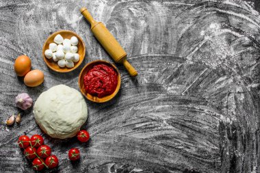 Hazır pizza. Soslu hamur, mozzarella ve domates. Rustik arka planda