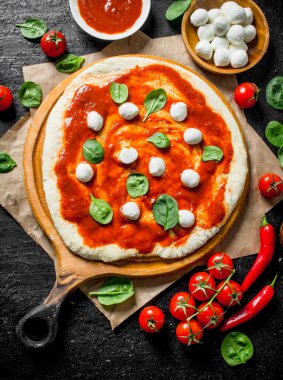 Çiğ pizza. Pizza için farklı malzemelerle hamur dışarı haddelenmiş. Rustik arka planda