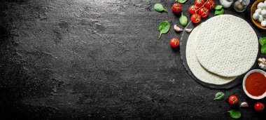 Mozzarella, domates salçası ve ıspanak ile yuvarlak pizza hamuru. Siyah rustik arka plan üzerinde