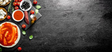 Hazır pizza. Pizza pişirmek için farklı malzemelerle Hamur. Siyah rustik arka plan üzerinde