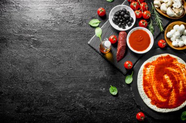 Hazır pizza. Pizza pişirmek için farklı malzemelerle Hamur. Siyah rustik arka plan üzerinde