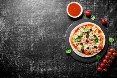 Çiğ pizza, kiraz domates, peynir, zeytin ve ıspanak. Koyu rustik arka plan üzerinde